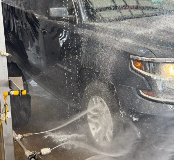 A close up photo of a black truck getting car wash wheel treatment at Clean Car Wash and Detail in Fredericksburg, VA.